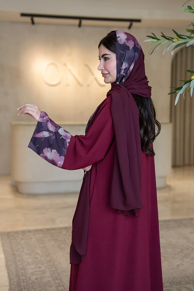 تصميم كريب ماروني بتركيبة أكمام مميزة تألقي بإطلالة أنيقة مع عباية باللون الماروني من قماش الكريب الناعم، تصميم بسيط يبرز بتفصيلة أكمام فريدة تجعلها قطعة لا تمر دون أن تُلاحَظ كريب ماروني بتركيبة أزهار على الأكمام تتميز هذه العباية بتركيبة قماش مطبوع بنقشة أزهار مائية بألوان البنفسجي والموف والرمادي الغامق تمتد على الجزء السفلي من الأكمام، تفصيلة تضيف عمقاً وتميزاً للتصميم في كل حركة الطرحه المتناسقة لإكمال إطلالتك لإضافة لمسة ختامية لإطلالتك، تأتي العباية مع طرحة ثنائية تجمع باللون الماروني مع نفس قماش الأزهار المطبوع لتكمل الإطلالة بتناسق مثالي، ارتديها بثقة في كل يوم يستحق حضورك