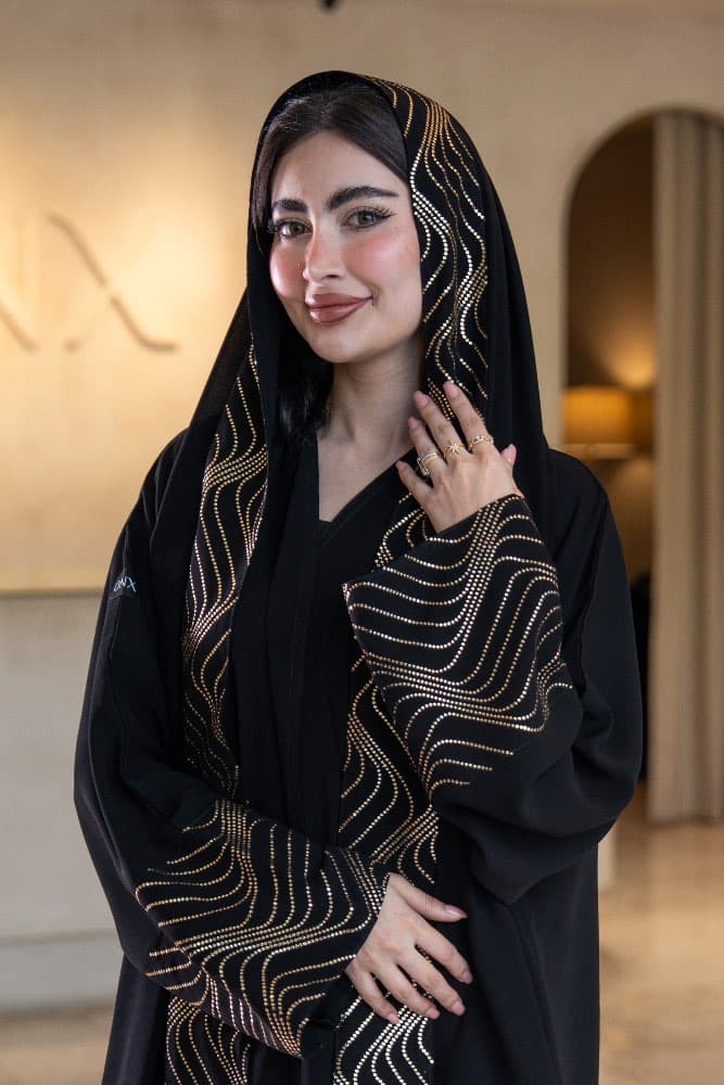 تصميم فاخر بتركيبة كريستال ذهبي
 عباية كريب أسود بتركيبة كريستال ذهبي بنقشات موجية على الأكمام، تفاصيل راقية تعطي العباية حضوراً مميزاً
 تركيبة كريستال ذهبي على الأكمام
 تتميز هذه العباية بنقشات موجية من الكريستال الذهبي على الأكمام، تفاصيل راقية تعكس جودة التنفيذ وتجعل العباية محور الإطلالة
 الطرحه المتناسقة لإكمال إطلالتك
 تأتي العباية مع طرحة سوداء تحمل نفس التركيبة الكريستالية الذهبية لتكمل الإطلالة بتناسق كامل، ارتديها بثقة في أي مناسبة