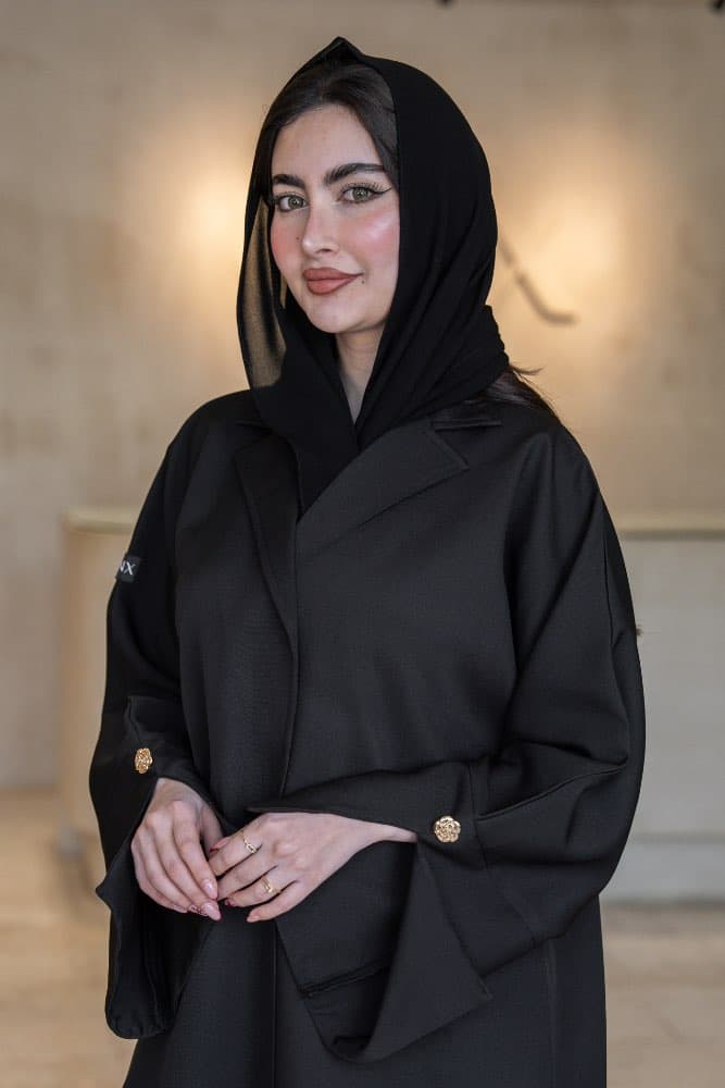 تصميم بليزر فاخر بلمسة ذهبية تألقي بإطلالة راقية مع عباية قماش باربي فاخر باللون الأسود، مصممة بقصّة بليزر عصرية تجمع بين الأناقة الهادئة والحضور القوي، ياقة واسعة بارزة تمنحك مظهراً مميزاً في كل مناسبة قماش باربي فاخر بسمك يعكس الفخامة تتميز هذه العباية بقماش باربي فاخر ذو ملمس مطفي وسمك واضح يعطي الإطلالة ثقلاً وفخامة حقيقية، أكمام بثنيات مزيّنة بأزرار ذهبية على شكل وردة تضيف تفصيلاً دقيقاً يرفع الإطلالة كاملة الطرحه المتناسقة لإكمال إطلالتك لإضافة لمسة ختامية لإطلالتك، تأتي العباية مع طرحة باللون الأسود تتناسق تماماً مع العباية وتكمل الإطلالة بأناقة، ارتديها بثقة في العمل والمناسبات وكل يوم يستحق حضورك