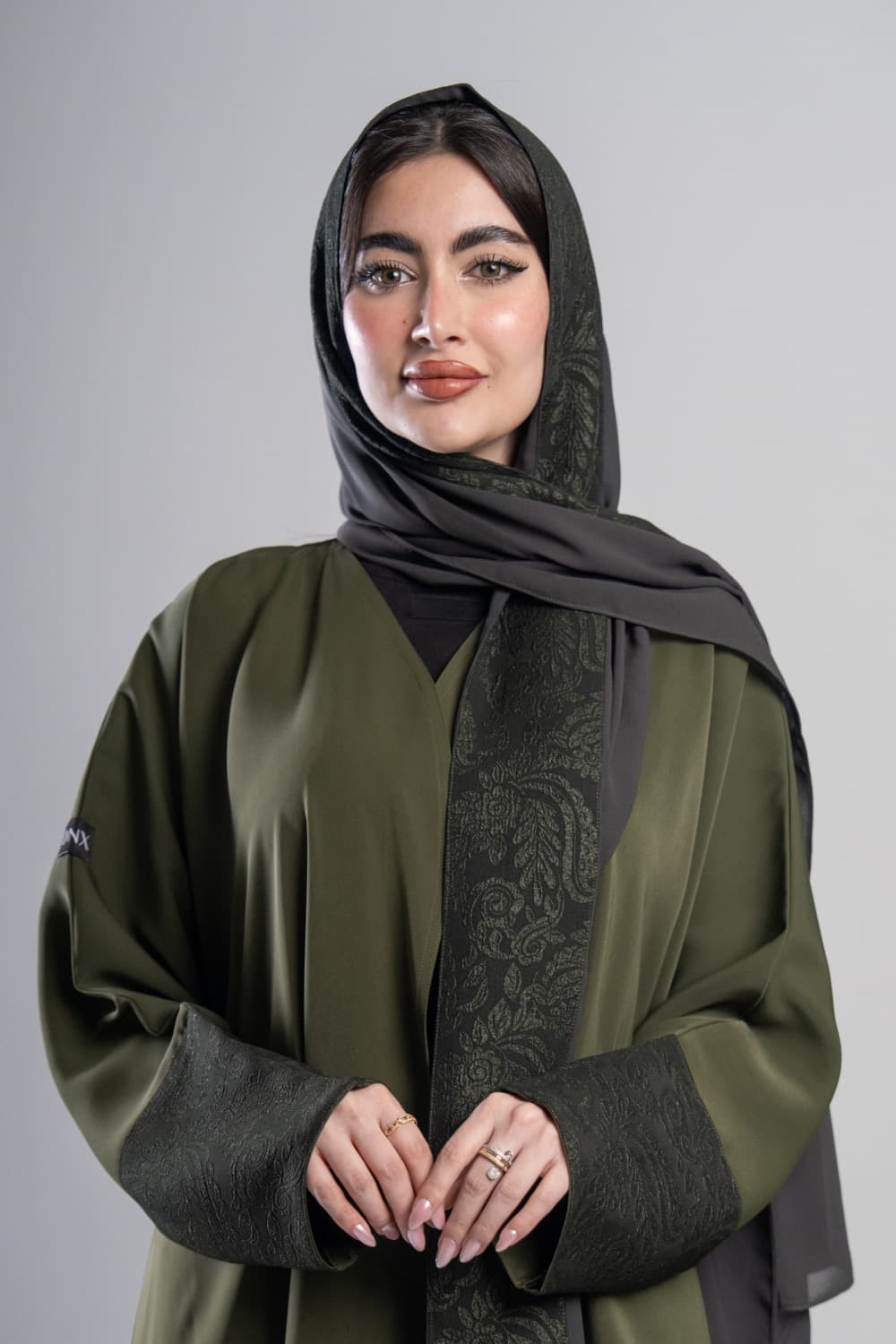 تألقي بعباية كريب أخضر زيتي
 عباية كريب أخضر زيتي بتركيبة من قماش أخضر داكن بنقشة زهرية على الأكمام، التدرج بين اللونين يعطي العباية طابعاً مميزاً وأنيقاً
 تركيبة قماش منقوش على الأكمام
 تتميز هذه العباية بتركيبة من القماش الأخضر الداكن المنقوش بنقشة زهرية على الأكمام، التفصيل يضيف عمقاً للتصميم ويجعله متكاملاً
 الطرحه المتناسقة لإكمال إطلالتك
 تأتي العباية مع طرحة تحمل نفس تركيبة القماش المنقوش لتكمل الإطلالة بتناسق كامل، ارتديها بثقة في أي مناسبة