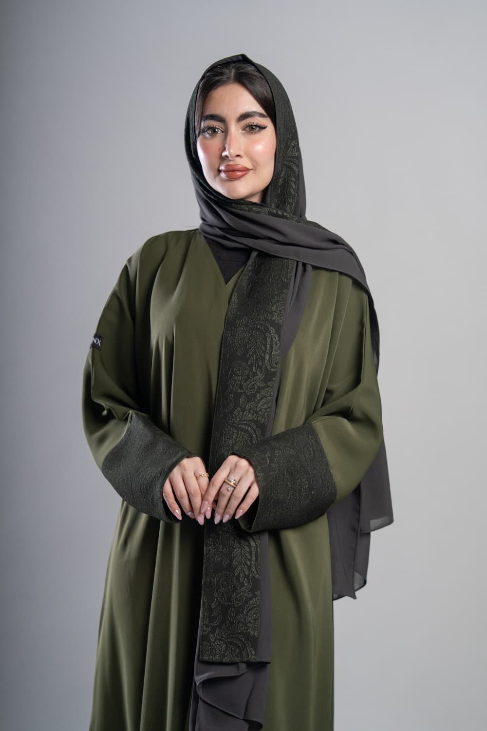 تألقي بعباية كريب أخضر زيتي
 عباية كريب أخضر زيتي بتركيبة من قماش أخضر داكن بنقشة زهرية على الأكمام، التدرج بين اللونين يعطي العباية طابعاً مميزاً وأنيقاً
 تركيبة قماش منقوش على الأكمام
 تتميز هذه العباية بتركيبة من القماش الأخضر الداكن المنقوش بنقشة زهرية على الأكمام، التفصيل يضيف عمقاً للتصميم ويجعله متكاملاً
 الطرحه المتناسقة لإكمال إطلالتك
 تأتي العباية مع طرحة تحمل نفس تركيبة القماش المنقوش لتكمل الإطلالة بتناسق كامل، ارتديها بثقة في أي مناسبة