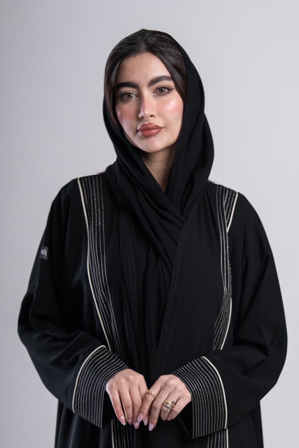 عباية كريب أسود بخطوط فضية وتطريز دقيق عباية كريب فاخر باللون الأسود تتميز بشريطين عموديين من التطريز الفضي الدقيق يمتدان من الكتف حتى أسفل العباية، مع خطوط رفيعة تمنحها طابعاً عصرياً وأنيقاً تطريز فضي وخطوط دقيقة تتخلل العباية خطوط تطريز فضية رفيعة تلمع عند انعكاس الضوء، محاطة بخطوط دقيقة تخلق تباينًا جميلاً مع الأسود، نفس التفصيل يظهر على الأكمام بشكل متناسق يرفع الإطلالة كاملة الطرحه المتناسقة لإكمال إطلالتك تأتي العباية مع طرحة شيفون باللون الأسود تتناسق مع العباية وتكمل الإطلالة بأناقة، ارتديها بثقة في العمل والمناسبات وكل يوم يستحق حضورك