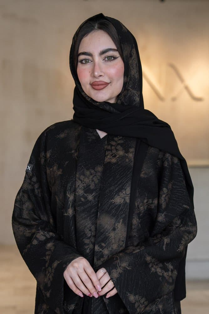 تصميم جاكار فاخر باللون الأسود والذهبي عباية باللون الأسود من قماش جاكار فاخر تحمل نقشات زهرية ذهبية منسجمة تمنحها حضوراً راقياً في كل مناسبة، قطعة تجمع بين الفخامة الهادئة والأناقة التي تلفت الأنظار قماش جاكار بنقشات ذهبية مميزة قماش جاكار ذو ملمس مميز يحمل نقشات زهرية ذهبية ضخمة منتشرة على خلفية سوداء غامقة، اللمعة الخفيفة في الخيوط الذهبية تضيف بريقاً دافئاً وراقياً يظهر في كل إضاءة، حافات أمامية بخط أسود أنيق يكمل شكل العباية بدقة الطرحه المتناسقة لإكمال إطلالتك تأتي العباية مع طرحة مصنوعة من نفس قماش الجاكار بنقشاته الذهبية مع بطانة من الشيفون الأسود الخفيف، تناسق تام يجعل إطلالتك متكاملة من الرأس حتى القدم